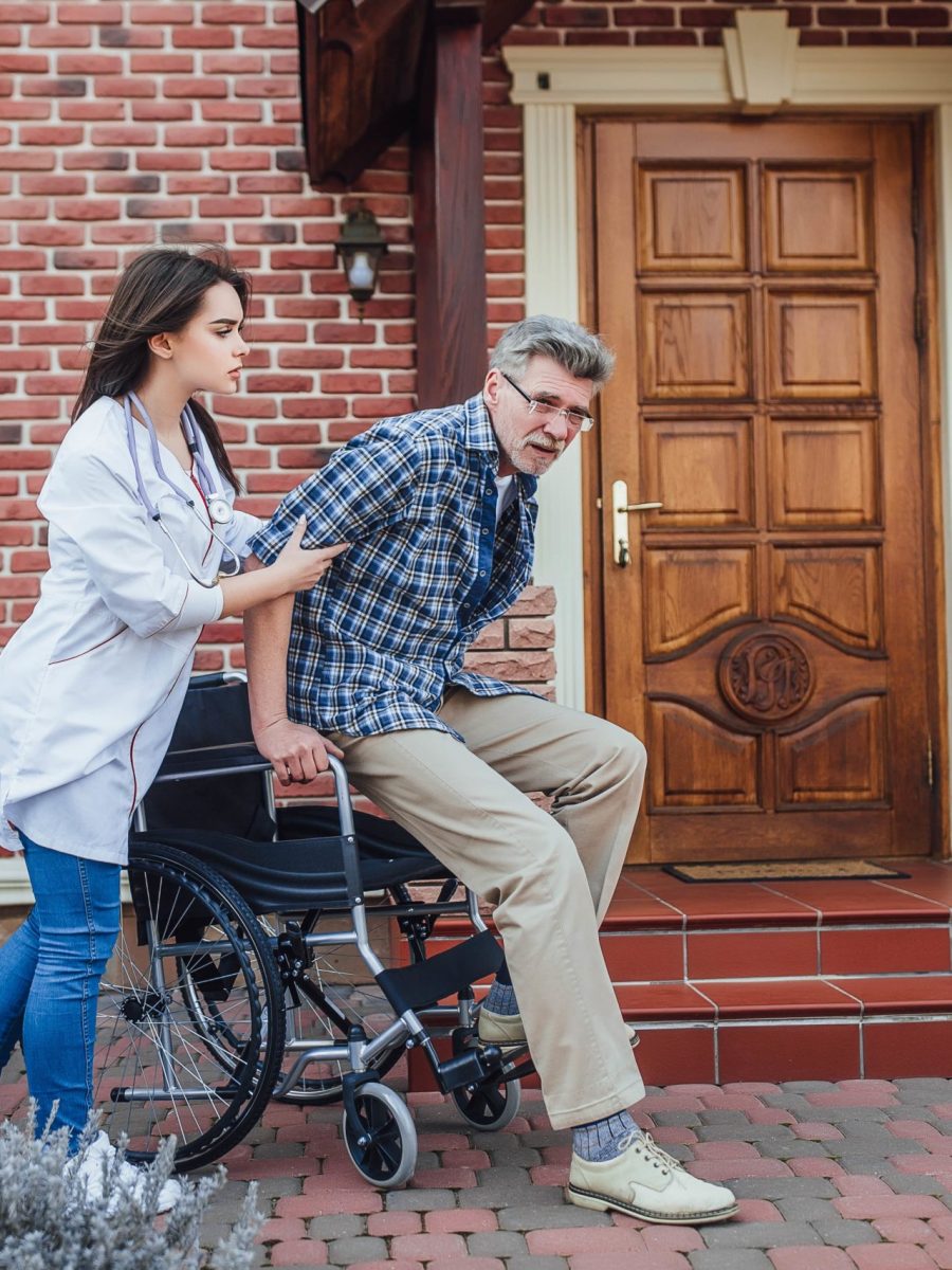 senior-man-sitting-wheelchair-with-smiling-nurse-takes-care-discussion-cheer-garden-nursing-home-min